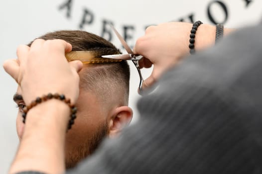 Haircut and alignment of the contour of the head with scissors. Short haircut in the barbershop.