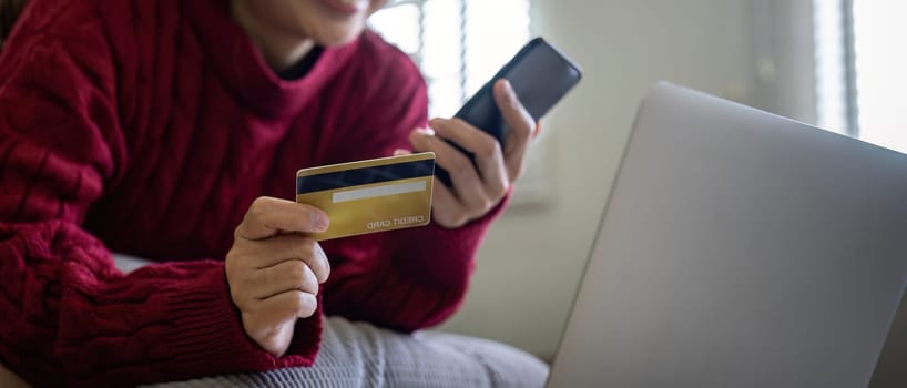 Young Asian woman hands holding credit card and using smartphone for internet purchase. Online shopping, Online payment at home.