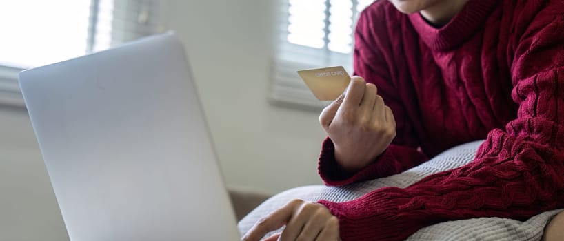 Young Asian woman hands holding credit card and using laptop for internet purchase. Online shopping, Online payment at home.