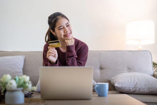 Young Asian woman hands holding credit card and using laptop for internet purchase. Online shopping, Online payment at home.