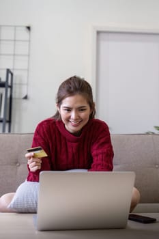 Young Asian woman hands holding credit card and using laptop for internet purchase. Online shopping, Online payment at home.