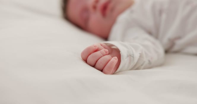 Hand, newborn and sleeping on bed in nursery with relaxing, resting and nap on blanket in morning. Baby, peaceful and dreaming in bedroom of home for child development, growth and nurture or relax.