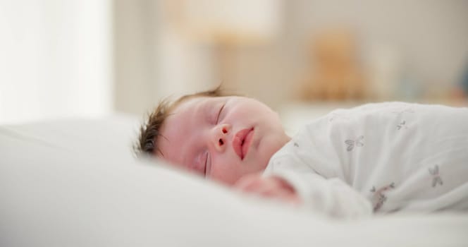 Tired, sleeping and newborn baby on a bed at a home in the bedroom for resting and dreaming. Cute, sweet and little infant, child or kid taking a nap in the morning in the nursery at family house