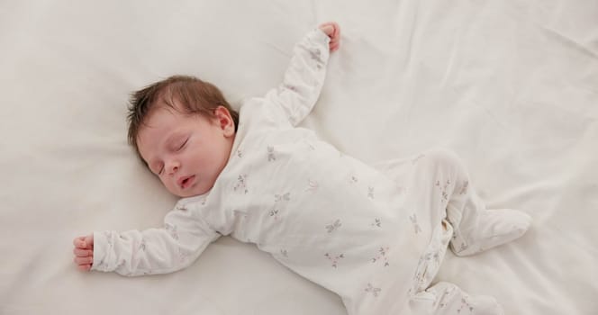 Sweet, sleeping and newborn baby on a bed at a home in the bedroom for resting and dreaming. Cute, tired and top view of infant, child or kid taking a nap in the morning in nursery at family house