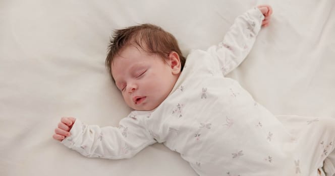 Cute, sleeping and newborn baby on a bed at a home in the bedroom for resting and dreaming. Tired, sweet and top view of infant, child or kid taking a nap in the morning in nursery at family house