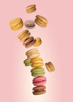 Multi-colored levitating macarons on a pink background