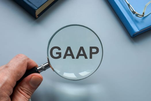 GAAP Generally Accepted Accounting Principles. A hand with magnifying glass points to an abbreviation.