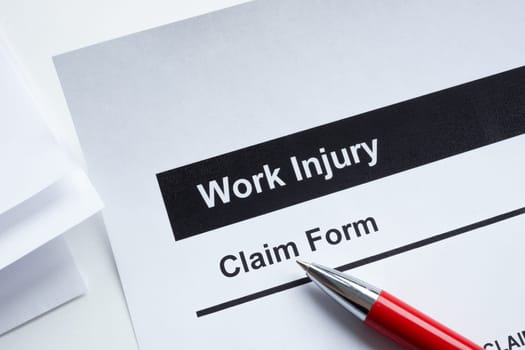 Work injury claim form, papers and pen.