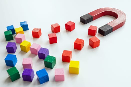 Talented employee or customer acquisition concept. The magnet attracts red cubes.