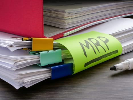 Stack of papers and sticker MRP Material requirements planning.