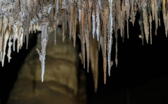 Stunning view of stalactites in a dark cave, providing a black background ideal for text placement.