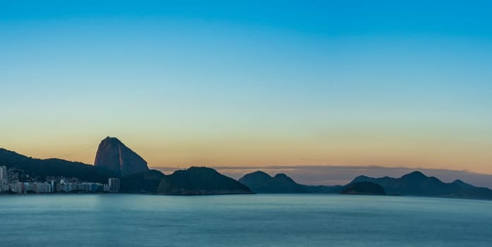 Dusk photo capturing Rio's mountains, Copacabana, and Sugarloaf with a silky water effect and clear sky, perfect for adding text.