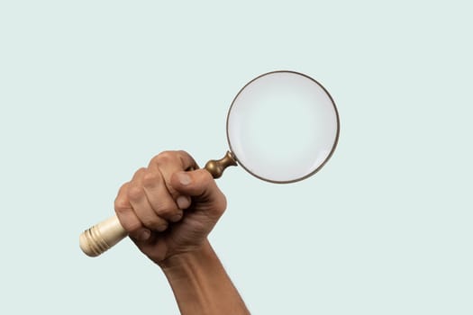 Black male hand holding a loupe or magnifying glass isolated on cyan. High quality photo