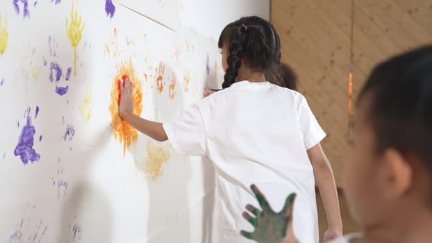 Diverse students put hands up together show colorful stained hands. Multicultural learner standing in front white background with stained hands while looking at camera. Creative activity. Erudition.