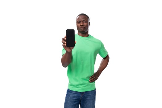 young american man dressed in green corporate t-shirt showing smartphone screen.