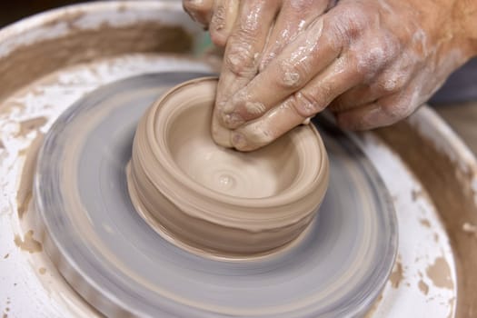 male hands creating cup on pottery wheel, Close-up