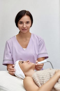 cosmetologist doing peeling procedure for female client in beauty salon