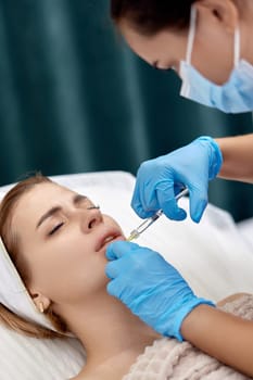 beautician makes injections to enlarge the lips of beautiful woman. procedure lip augmentation