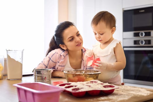 mother and little baby girl preparing the dough at the kitchen, bake cookies. happy time together