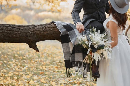 bride and groom kissing and holding beautiful bouquet in nature in autumn