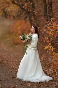 beautiful happy bride holding wedding autumn bouquet in nature