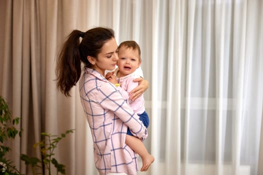 loving mother hugs her little crying daughter at home