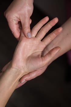 The masseuse massages the client's palms. Close-up of hands during a spa treatment. Vertical photo