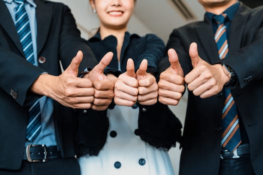 Many happy business people make thumbs up sign join hands together with joy and success. Company employee celebrate after successful work project. Corporate partnership and achievement concept. uds
