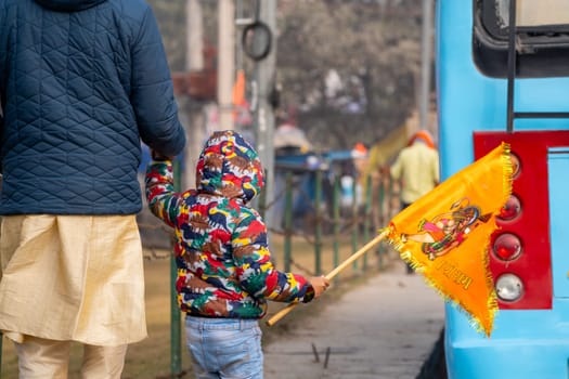 Ayodhya, Uttar Pradesh, India - 22nd Jan 2024: Young child face not visible carrying bhagwa saffron flag celebrating the Pran Pratishtha consecration of Ram mandir temple massive celebration in India