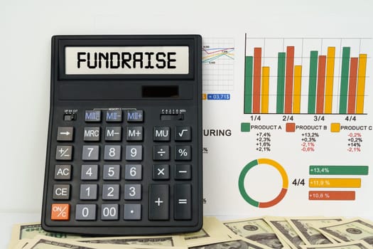 Business concept. On the table are financial reports, dollars and a calculator with the inscription - Fundraise