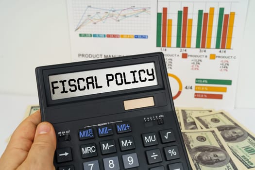 Business concept. On the table there are financial reports, dollars, in the hands of a calculator with the inscription - Fiscal policy