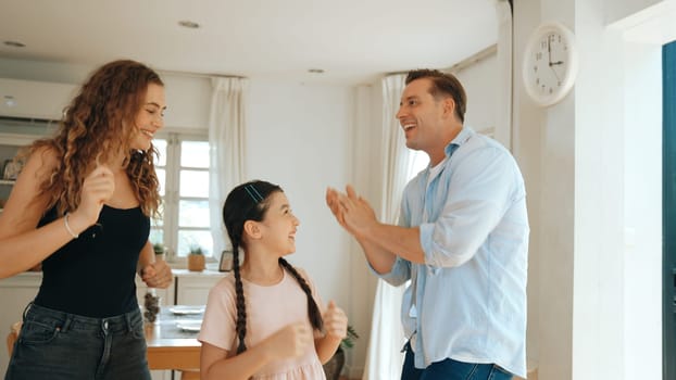 Happy family portrait with lovely little girl smiling, lovely and cheerful parent and their daughter sitting together in living room at home with warm daylight. Synchronos