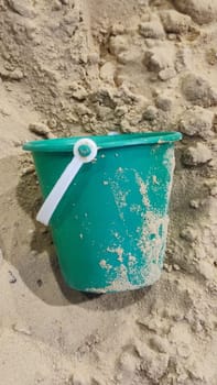 green plastic bucket lies in the sand, children's toy, object, beach. High quality photo