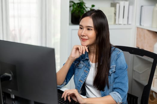 Working young beautiful asian creative manager focusing on pc, creating with new website design on new social media online channel planning with blue jeans shirt at modern home office. Stratagem.