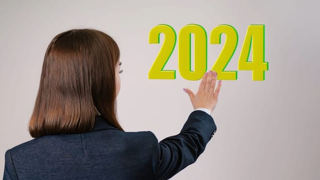 business woman with the new year 2024 for her hand. Businesswoman pressing 2024 gold color letter over grey background, Business happy new year 2024 cover concept. High quality image