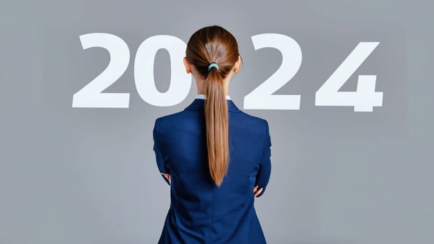 business woman with the new year 2024 for her eyes. Businesswoman looking at 2024 white color letter over grey background, Business happy new year 2024 cover concept. High quality image