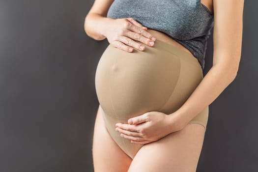 Pregnant bliss: Mom-to-be embraces her baby bump with a soft fabric bandage, providing gentle support. Maternity made comfortable.