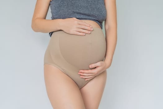 Pregnant bliss: Mom-to-be embraces her baby bump with a soft fabric bandage, providing gentle support. Maternity made comfortable.