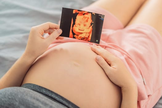 Expectant mother tenderly connects with her unborn child, holding ultrasound photo to her pregnant belly.