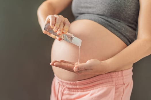 Expectant mom ensures safety, applying gel sanitizer for a clean and healthy pregnancy.