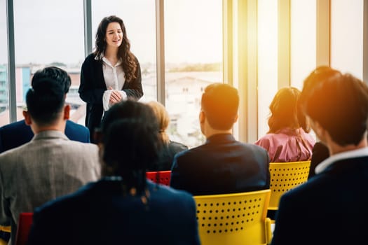 A meeting of diverse business professionals in an office setting. Seated team members actively engage in discussions, while male and female managers stand, facilitating effective communication.
