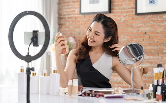 Asian Woman influencer shoot live streaming vlog video review makeup uttermost social media or blog. Happy young girl with cosmetics studio lighting for marketing recording session broadcasting online