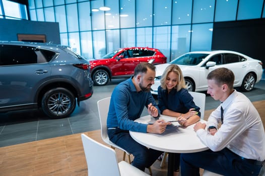 Happy caucasian couple signs a contract for the purchase of a car salon