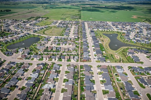 Drone image capturing the town of Warman in Saskatchewan during the summer season, highlighting its suburban and residential areas surrounded by lush greenery and vibrant atmosphere