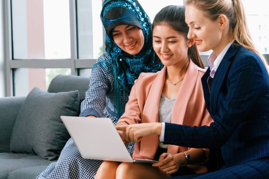 Multicultural working group. Team of businesswomen of different ethnicity, Caucasian, Asian and Arabic working together with laptop computer at office workplace. Multiethnic teamwork concept. uds