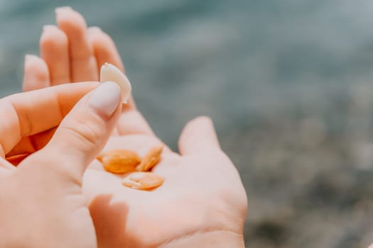 Woman eating milky almond nuts. A young caucasian woman choping fresh green almond after morning fitness yoga near sea. Only hands are visibly. Healthy vegan food. Slow motion. Close up