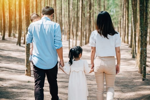 Happy family walking through the sunny forest, holding hands and enjoying the beautiful springtime views, Happy family day