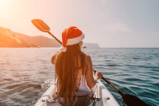 Woman in kayak back view. Happy young woman with long hair floating in transparent kayak on the crystal clear sea. Summer holiday vacation and cheerful female people relaxing having fun on the boat