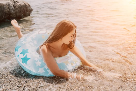 Woman summer sea. Happy woman swimming with inflatable donut on the beach in summer sunny day, surrounded by volcanic mountains. Summer vacation concept