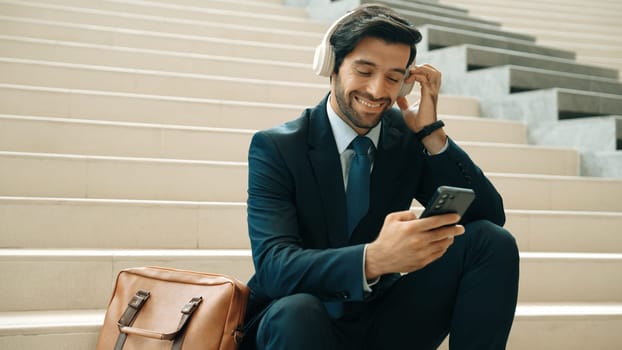 Smart business man listening and enjoy music while wear headphone. Profession project manager smiling while getting good news, getting promotion, increasing sales. Relaxing man enjoy music. Exultant.